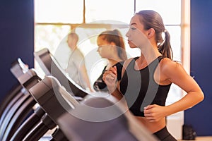 Close up young fit women on modern treadmill in gym