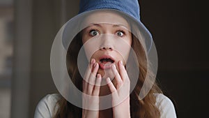Close-up young frightened surprised woman standing indoors with wide open eyes and mouth in fright scared girl shocked