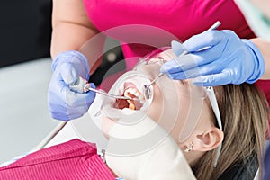 Close-up a young girl in a dentist`s chair undergoes a routine diagnosis after removing braces with cleaning and sizing