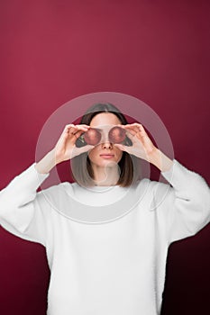 Close up of young girl holding 2 Christmas balls near her eyes