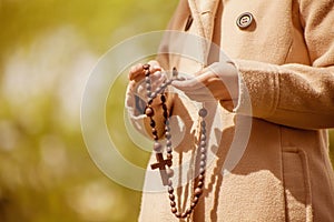 Close up young girl holding rosary and praying to God