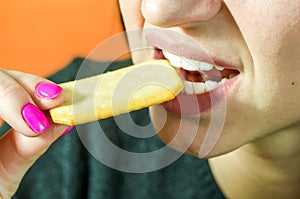 Close up of a young girl lips and teeth eating cookie or biscuit, selective focus