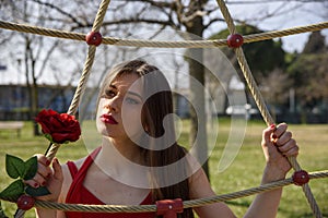 Close-up of young girl with red rose in a public park.