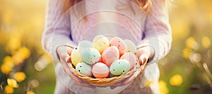 Close-up of young girl standing in a meadow and holding a basket with painted Easter eggs