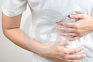 Close-up of a young girl with stomachache using his hand to press his stomach. Upset people, stomachache, gastritis, indigestion