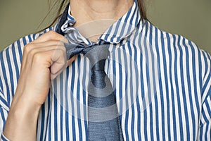 Close up of a young girl in a striped blue shirt and tie, business clothes, an office worker in a suit