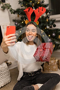 Close up of young girl telephone to parents and show a red Christmas gift and her tongue