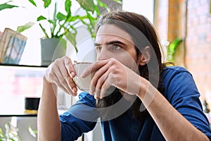 Close up of young handsome man holding drinking cup of coffee