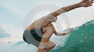 Close-up of a young handsome surfer struggling to unbend on the wave and starting and passing the wave with indecent