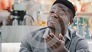 Close-up young happy african american man talking through wireless headphones smiling answering friendly business call