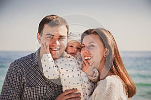 Close up of young happy loving family with small kid in the middle, having fun at beach together near the ocean, happy lifestyle f