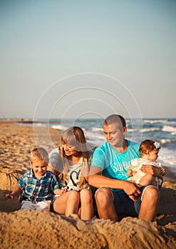 Close up of young happy loving family with small kids, having fun at beach together near the ocean, happy lifestyle family concept