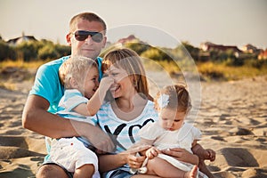 Close up of young happy loving family with small kids in the middle, having fun at beach together near the ocean, happy lifestyle