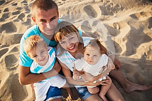 Close up of young happy loving family with small kids in the middle, having fun at beach together near the ocean, happy lifestyle