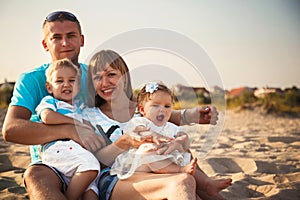 Close up of young happy loving family with small kids in the middle, having fun at beach together near the ocean, happy lifestyle