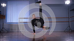 Close up of young hip-hop dancer in black trousers and pullover performing handstand as an element of urbanstyle and