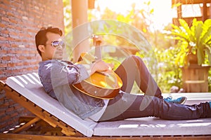 Young hipster man practiced guitar in the park,happy and enjoy playing guitar. photo