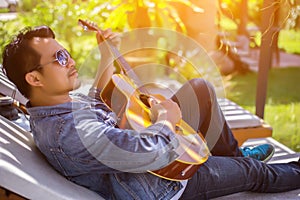 Young hipster man practiced guitar in the park,happy and enjoy playing guitar. photo