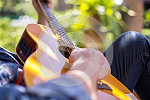 young hipster man practiced guitar in the park,happy and enjoy playing guitar. photo