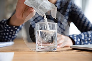 Woman pouring soluble anti-influenza powder in glass of water. photo