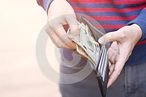 Close up young male holding an wallet in the hands of an man take money out of pocket. expenses finance