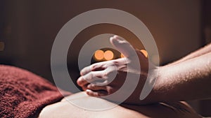 Close-up Young male massage therapist does back massage to a woman with a tattoo in a massage room with dim lights on