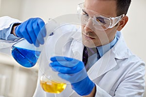 close up of young male scientist with flask making test or research.