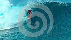 CLOSE UP: Young male surfer enjoying the summer by surfing a big emerald wave.