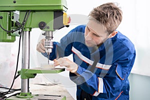 a close up young male worker using a drill machine on the factory