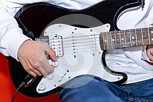 Close up of a Young man adjusting electric guitar volume. Music, instrument education, entertainment