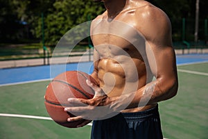 Close-up young man, african male basketball player playing basketball at street public stadium, sport court or