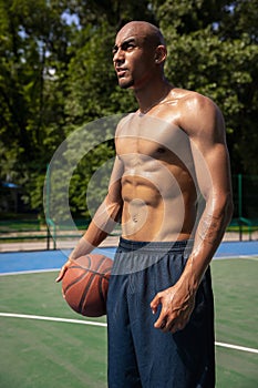 Close-up young man, african male basketball player playing basketball at street public stadium, sport court or