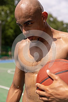 Close-up young man, african male basketball player playing basketball at street public stadium, sport court or