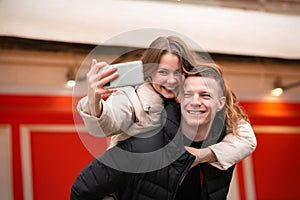 Close-up of a young man carrying a beautiful woman on his back. The couple takes a photo
