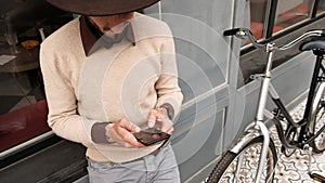 Close up young man in casual clothes with bicycle surfing internet on smartphone