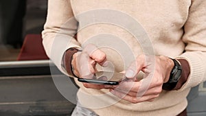 Close-up young man in casual clothes surfing internet on smartphone