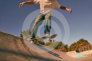 Close up of young man doing tricks on his skateboard at the skate park. Active sport concept