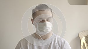 Close-up of young man in face mask disagree in online chat. Portrait of Caucasian male employee working from home. Covid