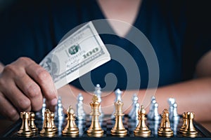 Close-up of an young man hand holding dollar currency playing chess