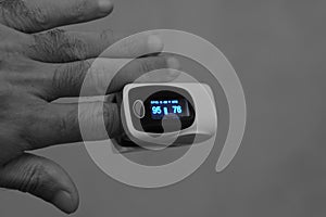 Close-up for a young man hand with a pulse oximeter that measures the oxygen saturation of the blood and the pulse rate