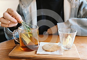 Close up young man hand putting rosemary into the hot tea for afternoon tea time break, cozy at home