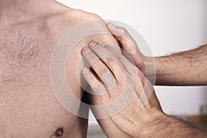 Close-up of a young man having chiropractic shoulder adjustment. Physiotherapy, sports injury rehabilitation. Osteopathy,