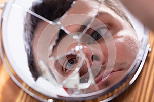 Reflection Of A Man`s Face In Broken Mirror