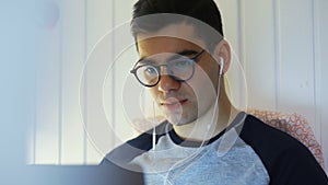 Close-up a young man is lying on a bed and working on a laptop, typing on a keyboard, working at night, remote work from