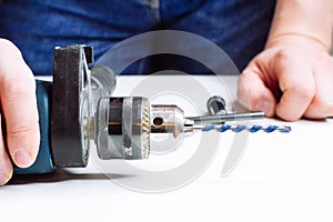 Close up of young man is preparing electric drill and changing drill bit