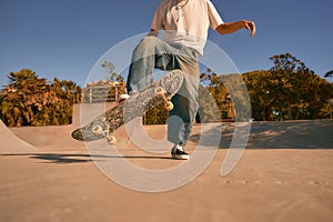 Close up of young man riding skateboard in skate park on sunny day. Extreme sport concept