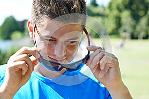Close Up Of Young Man Running In Park Putting On Sunglasses