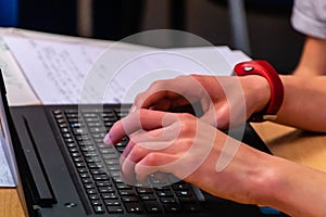 A close-up of a young man`s hands typing on the laptop keyboard while working in the office