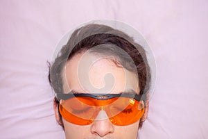 Close up of young man sleeping wearing red sleep glasses with blue light filtering lenses