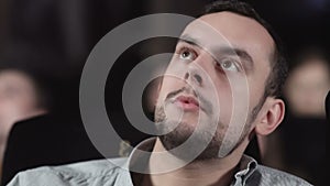 Close up of Young man is watching movie and talking with somebody at cinema